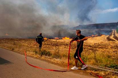Un bombero y un voluntario intentan sofocar las llamas en un incendio forestal, en Velestino, prefectura de Magnesia, Grecia, este 27 de julio. 
