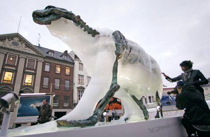 Los visitantes observan c&oacute;mo se derrite una escultura de un oso polar para mostrar un esqueleto de hierro. 