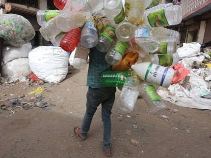 Un trapero carga a su espalda con botellas y bidones de plástico en las calles de la ciudad india de Bhopal, el pasado junio.