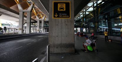 Un hombre espera sentado frente a la fila de taxis de la T4 de Madrid, vacía durante el pasado martes por la huelga de estos profesionales.