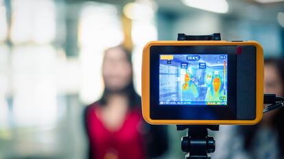 Asian people waiting for body temperature check before access to building for against epidemic flu covid19 or corona virus from wuhan in office by thermoscan or infrared thermal camera