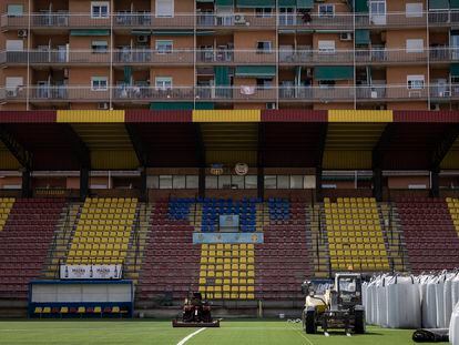 El estadio del Sant Andreu, en obras por el cambio de césped, con los bloques del barrio detrás.