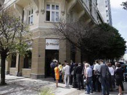 Grupos de personas hacen cola para sacar dinero en un banco búlgaro, en Sofía.