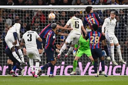 El defensa español del Real Madrid Nacho Fernández (C) cabecea el balón en el area del Barcelona