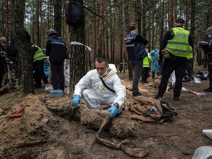 Un técnico examina un cadáver exhumado de una fosa común en Izium, este viernes.