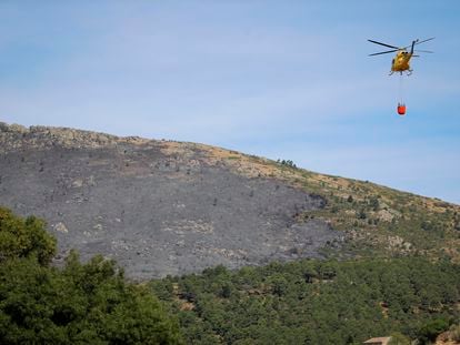 Un helicóptero transporta agua para vertirla sobre el incendio forestal originado en el término municipal de Robledo de Chavela.