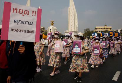 Trabajadoras disfrazadas de embarazadas sostienen pancartas mientras asisten a la manifestación del Día Internacional de la Mujer en Bangkok (Tailandia).