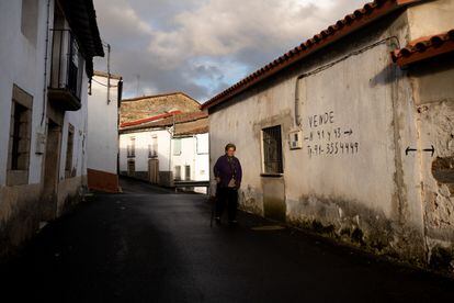 Una vecina de Alcañices (Zamora) pasa por delante de una vivienda en venta en la localidad.