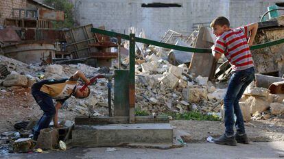 Dos ni&ntilde;os sirios beben de un pozo en la ciudad de Arbin, a las afueras de Damasco.