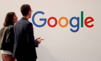 Dos personas pasan junto al logotipo de Google en París.