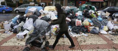 Una mujer pasa ante la basura acumulada en una calle de Pinto.