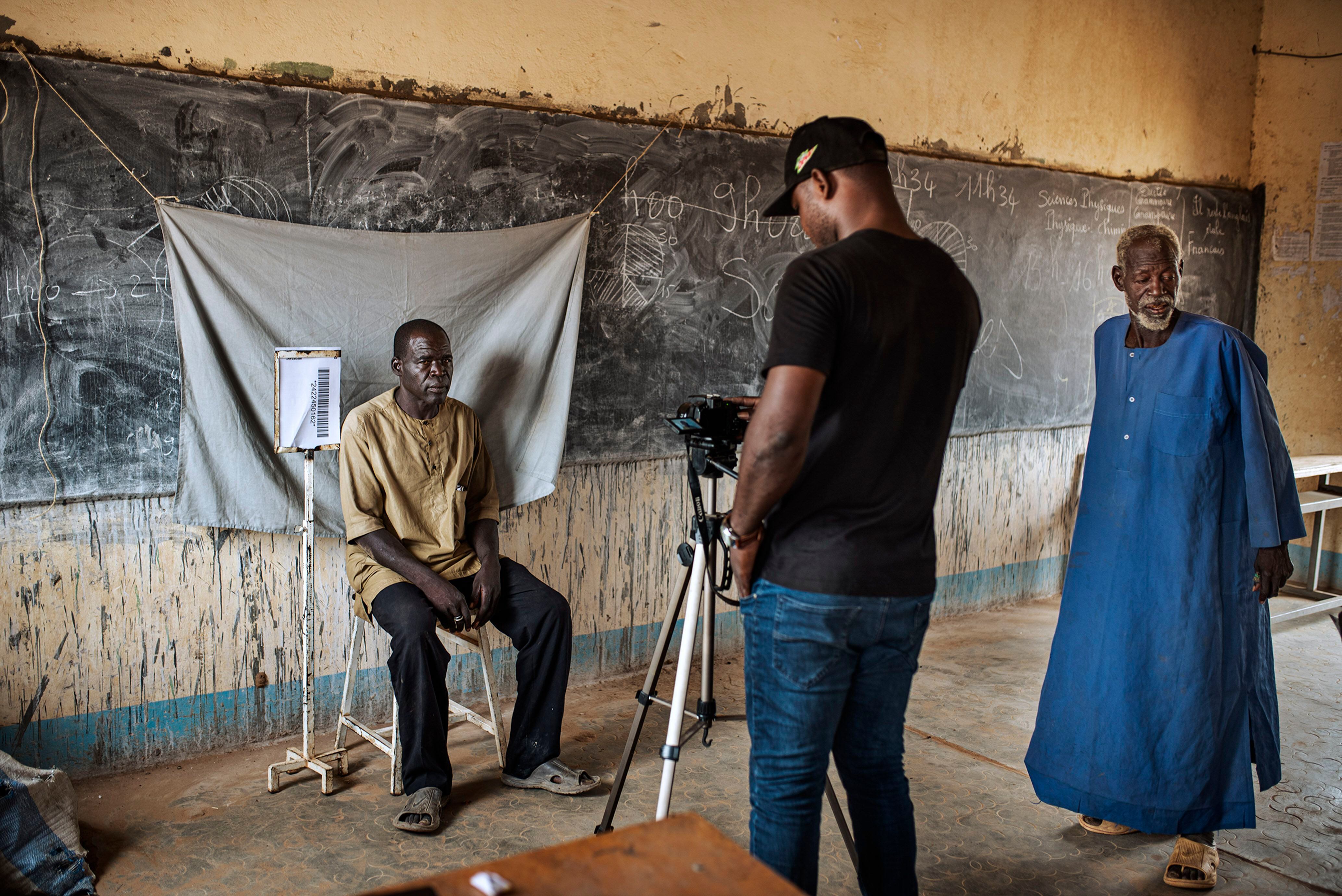 Un trabajador de la administración toma una fotografía y los datos personales de un desplazado para inscribirlo en un registro en el Instituto de Barsalogho, en el centro de Burkina Faso.