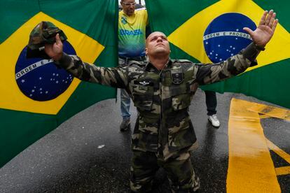 Un bolsonarista vestido con ropa militar, se arrodilla frente a un par de banderas brasileñas durante una de las manifestaciones de este miércoles, en Río de Janeiro.