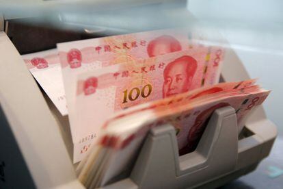 Una m&aacute;quina cuenta billetes de 100 yuanes en un banco de Pek&iacute;n.