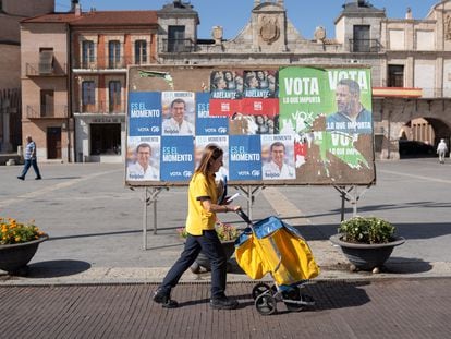 Elena Olivar pasa con su carro por delante de los carteles electorales ubicados en la Plaza Mayor de Medina del Campo.