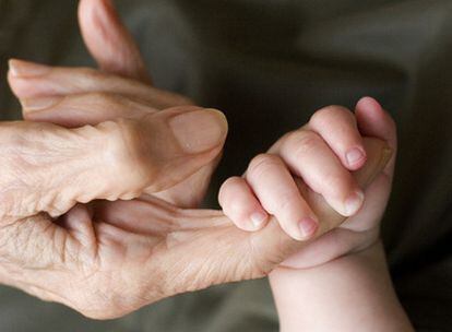 Una niña agarra con fuerza la mano de su bisabuela.