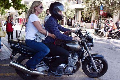 El exministro de Finanzas griego Yanis Varoufakis conduce su motocicleta por una calle de Atenas llevando en la parte trasera a su mujer Danae Stratou.