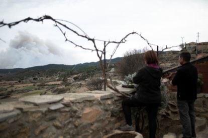 Dos personas se asoman para ver el humo del incendio en el municipio de San Agustín, en Teruel, este viernes.