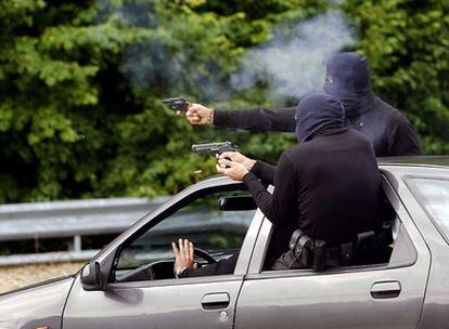 Dos escoltas disparan un revólver y una pistola desde un coche a toda velocidad, simulando la respuesta a un intento de atentado.