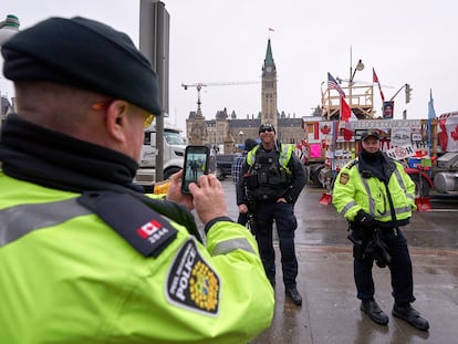 Un policía le toma fotos a sus colegas frente al parlamento mientras los camioneros protestan contra los mandatos de vacunación en el centro de Ottawa, Canadá.