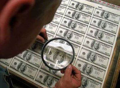 Un funcionario de la Fed revisa un pliego de billetes de 100 dólares.