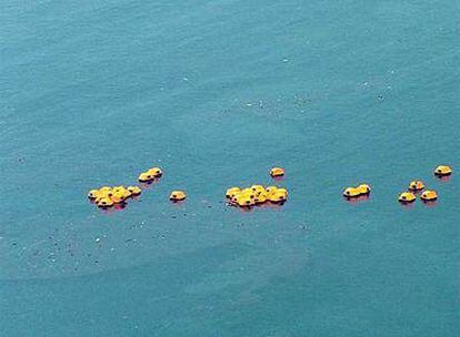 Los botes salvavidas del <i>Sea Diamond</i> flotan tras su hundimiento entre restos fuel. .