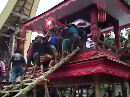 Varios personas transportan un ataúd por unas escaleras de bambú.