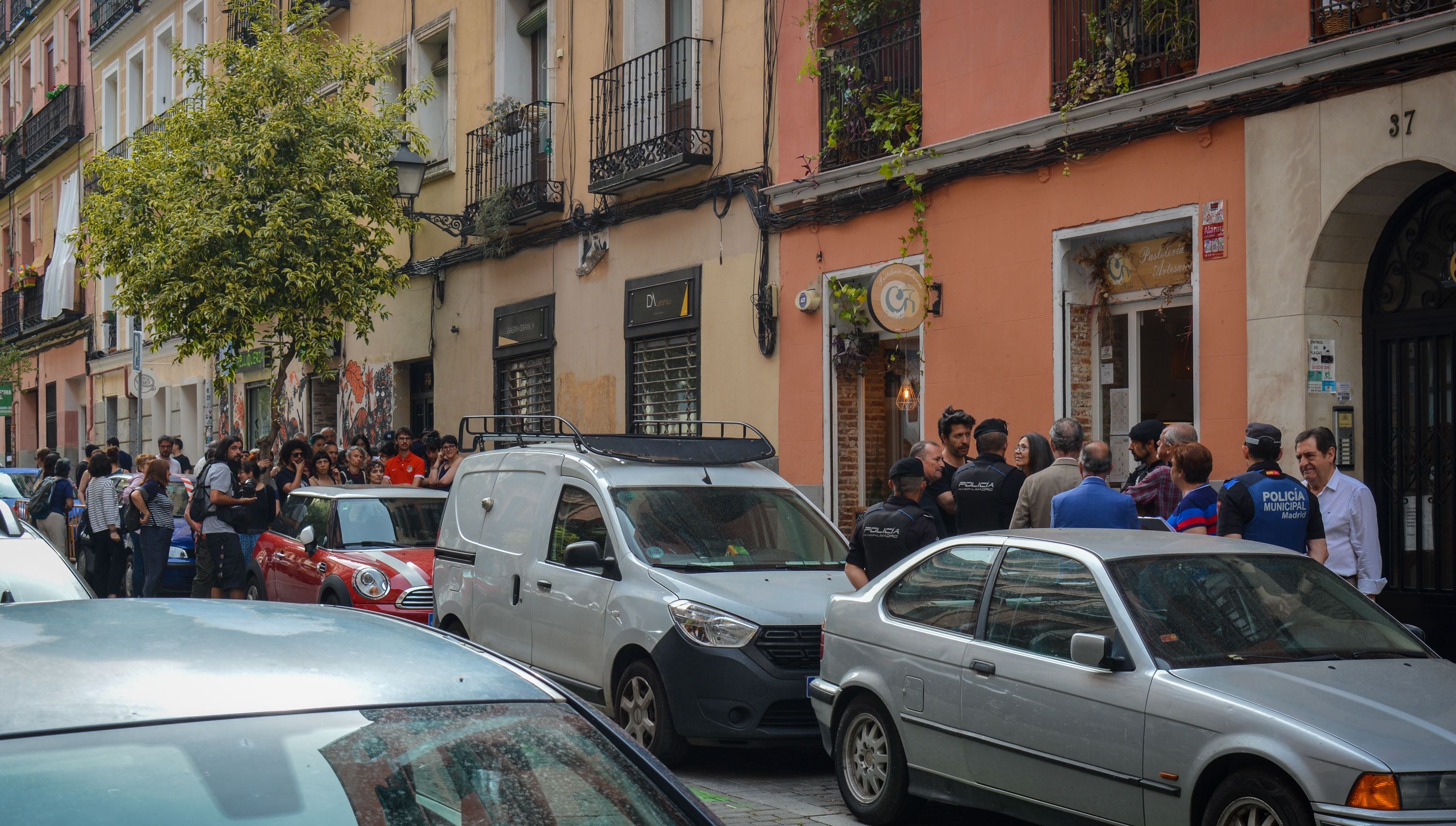 En primer plano, un grupo de vecinos intenta aplazar el desahucio de Marina López; de fondo, unas 40 personas bloquean la entrada al edificio donde vive la inquilina.