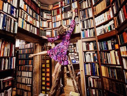 Una mujer busca un libro en una biblioteca.