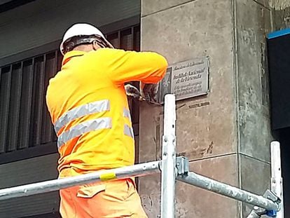 Un operari retira la placa franquista d'un edifici del carrer de Còrsega.