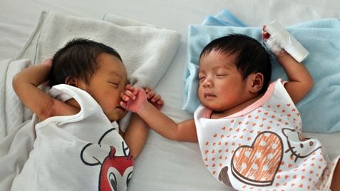 Dos bebés duermen en una cama en la llamada 'fábrica de bebés' de Manila.