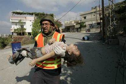 Un miembro de la Defensa Civil lleva en sus brazos a una niña rescatada del edificio destruido