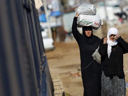 Refugiados sirios trasladan bolsas de alimentos este martes en el paso fronterizo de &Ouml;nc&uuml;pinar, Turqu&iacute;a.