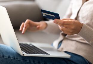 Close up woman shopping, paying by credit card, buying goods or ordering online, using laptop, login internet bank service, typing on keyboard, checking balance, sitting on sofa at home