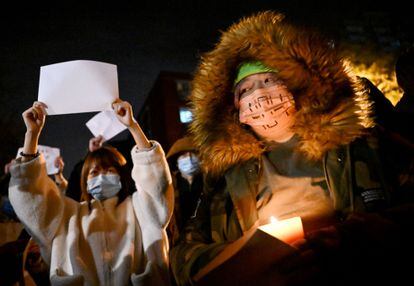 Una persona sujeta una vela mientras otra sostiene un folio en blanco durante la protesta en Pekín.