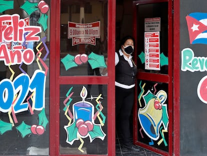 Una mujer se asoma desde la entrada a una cafetería, en La Habana.