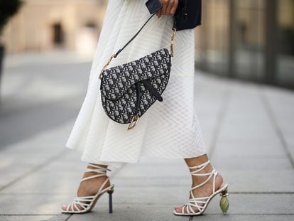 Una mujer pasea por las calles de París con un bolso de Dior.