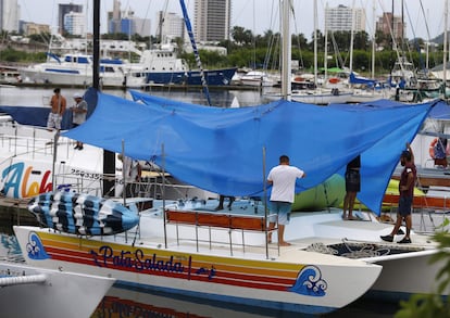 Un grupo de hombres toman medidas para proteger un catamarán en una marina de Mazatlán antes de la llegada de 'Orlene'.
