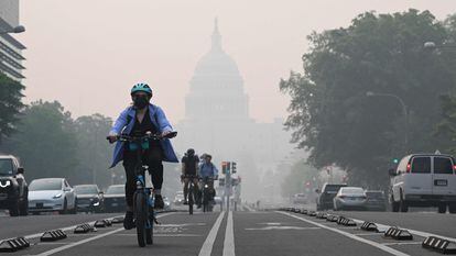 A cyclist rides under a blanket of haze partially obscuring the US Capitol in Washington, DC, on June 8, 2023. Smoke from Canadian wildfires have shrouded the US East Coast in a record-breaking smog, forcing cities to issue air pollution warnings and thousands of Canadians to evacuate their homes. The devastating fires have displaced more than 20,000 people and scorched about 3.8 million hectares (9,390,005 acres) of land. Prime Minister Justin Trudeau described this wildfire season as the country's worst ever. (Photo by Mandel NGAN / AFP)