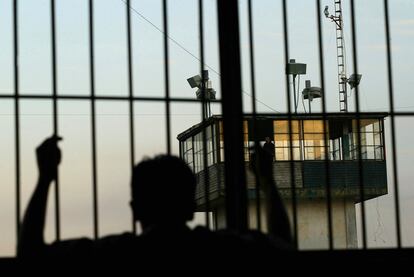 Un recluso mira desde detrás de las rejas una torre de seguridad en la prisión estatal de Nayarit, en Tepic (México).