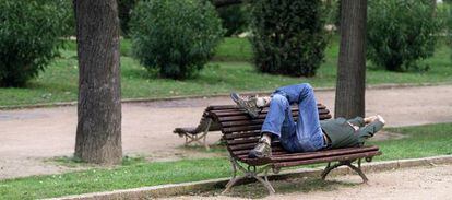 Un hombre se echa la siesta en un parque de Barcelona.