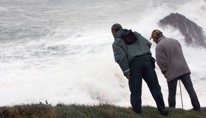 Dos personas se asoman al acantilado de Punta Langosteira (A Coruña), en el que una ola se tragó el lunes a tres personas.