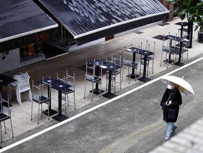 Una mujer pasa por delante de una terraza de un bar vacía, este lunes en Oviedo.