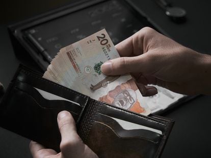 En una imagen de archivo, un hombre toma billetes de 20 mil pesos colombianos.