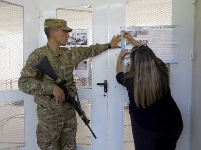 Un soldado ayuda a un oficial electoral a pegar una hoja de reglas para votar en un colegio electoral en Buenos Aires. 