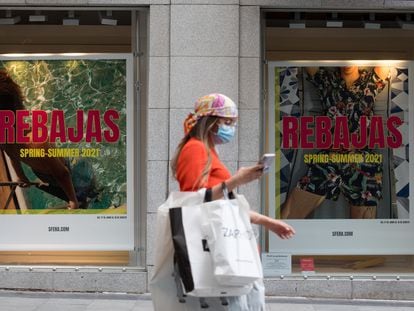 Una mujer pasa frente a un escaparate en el que se anuncia el inicio de las rebajas, este miércoles en Madrid.