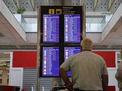 Dos turistas observan un panel de horarios en el aeropuerto de Palma de Mallorca.