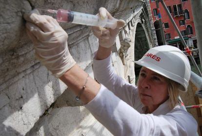 La restauradora Elisabetta Ghittino, inyecta alcohol en una piedra dañada del puente de Rialto.