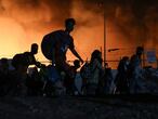 Refugees and migrants carry their belongings as they flee from a fire burning at the Moria camp, on the island of Lesbos, Greece, September 9, 2020. REUTERS/Elias Marcou