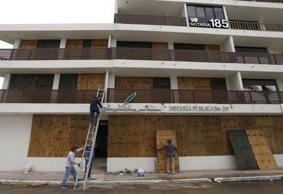 Trabajadores tapan las ventanas de un edificio frente al mar, en Mazatlán. Se espera que el huracán toque tierra en la costa norte de Nayarit y la costa sur de Sinaloa.